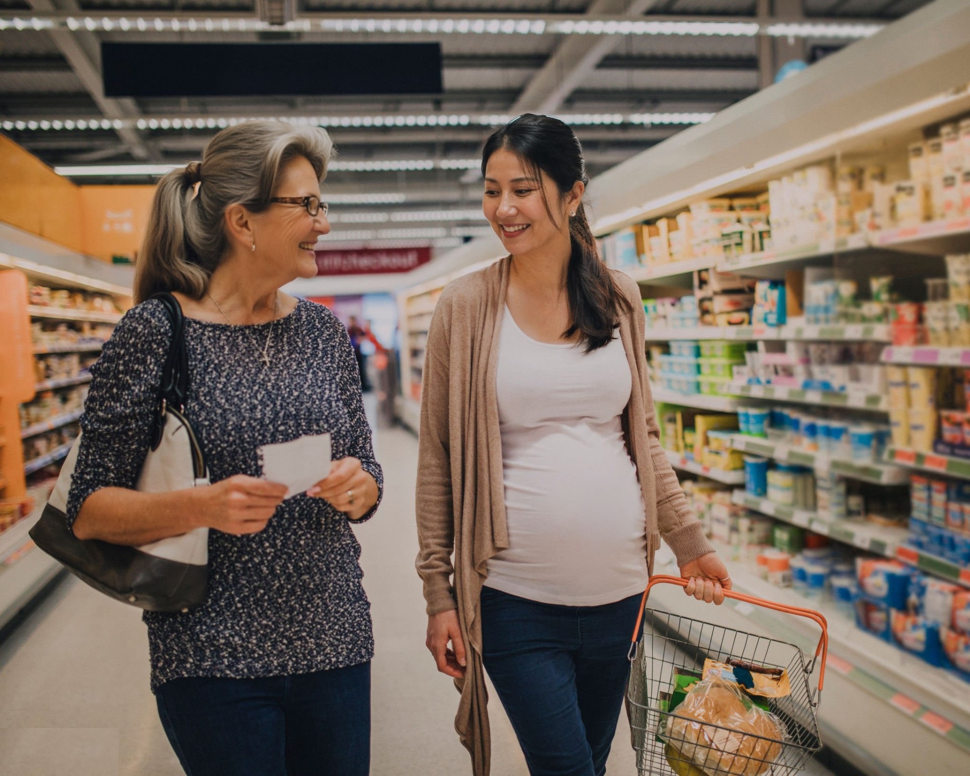 Begleiterin geht gemeinsam mit einer Kundin durch den Supermarkt und unterstützt beim Einkauf.